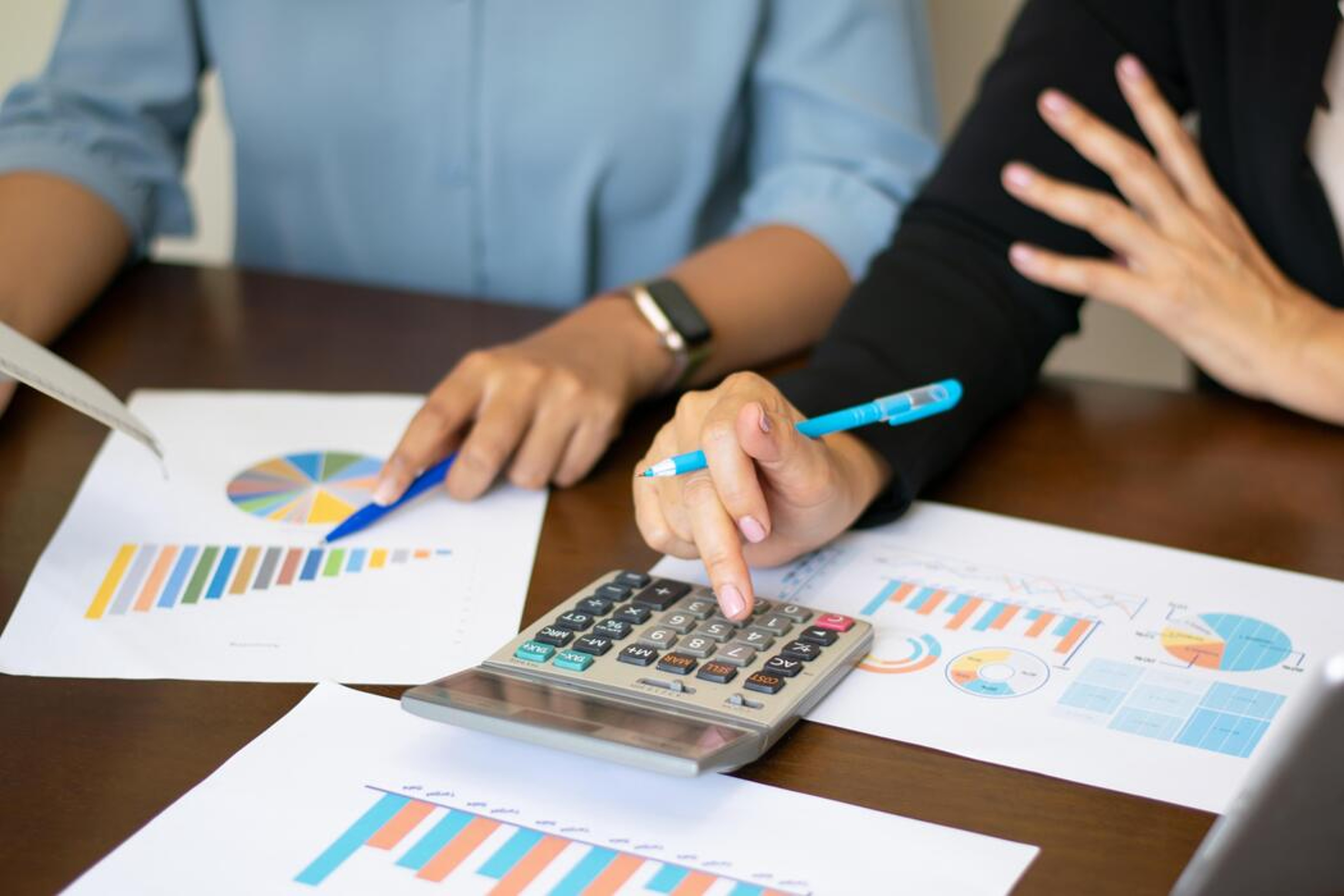 An advisor and client reviewing financial charts and calculating figures together